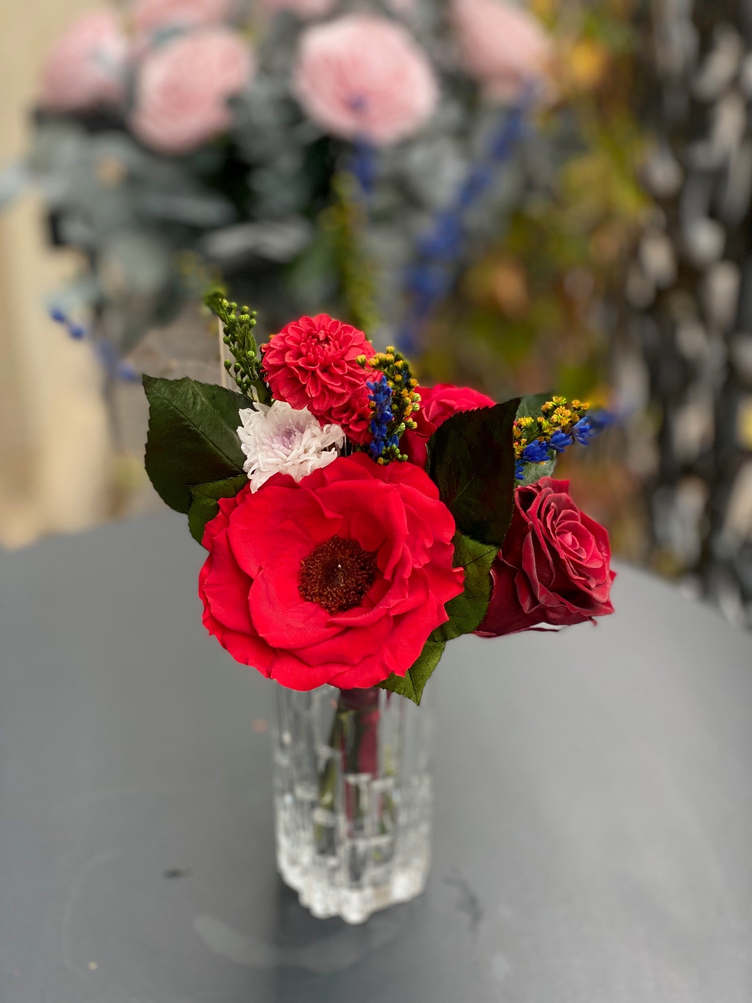 Bouquet éternel Matisse : fleurs stabilisées rouge intense avec touches cobalt et blanc, dans un vase en cristal.